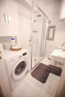 a bathroom with a washing machine and a shower at Sunny Garden Apartment kolonaki in Athens