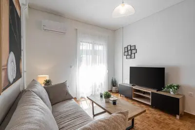 a living room with a couch and a flat screen tv at LIV - Trendy Athenian Apartment in Pagrati in Athens