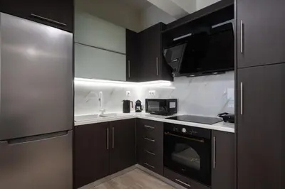 a kitchen with black cabinets and a sink and a stove at LIV - Relaxing Pagrati Retreat in Athens in Athens