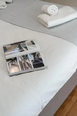 a magazine on the side of a white bed at LIV - Relaxing Pagrati Retreat in Athens in Athens
