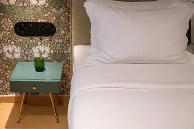 a bed with a night stand next to a bed with a pillow at Athens Retro in Athens