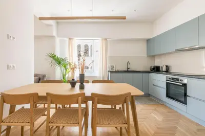 a kitchen and dining room with a wooden table and chairs at Chic & Spacious 3BR Apartment at National Museum by UPSTREET in Athens
