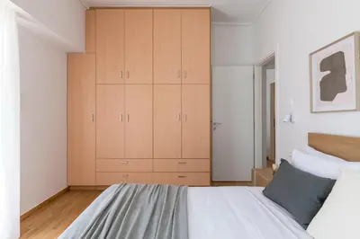 a bedroom with a large bed and wooden cabinets at Chic & Spacious 3BR Apartment at National Museum by UPSTREET in Athens