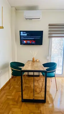 a dining room table with two chairs and a tv at Ilisia mini suite in Athens