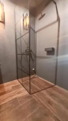 a glass shower in a room with a wooden floor at The Black key in Athens