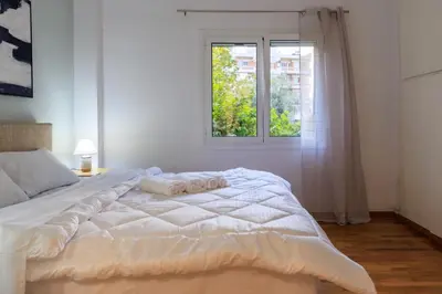 a bedroom with a white bed with two towels on it at Aiolos Elegant retro suite in GLYFADA centre in Athens