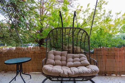a chair and a table in front of a fence at Aiolos Elegant retro suite in GLYFADA centre in Athens