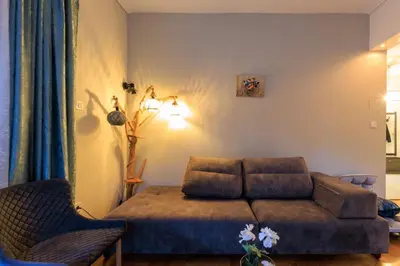 a living room with a couch and a chair at Aiolos Elegant retro suite in GLYFADA centre in Athens