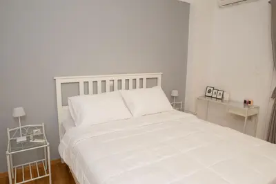 a white bed in a white bedroom with two tables at M23 by SpitiSou in Athens