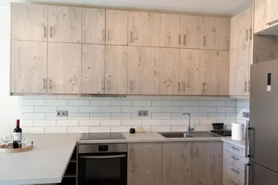 a kitchen with wooden cabinets and a sink and a refrigerator at Palm & Pearl Apartment in Athens
