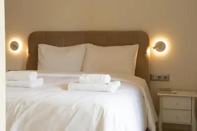 a white bed with two towels on top of it at Palm & Pearl Apartment in Athens