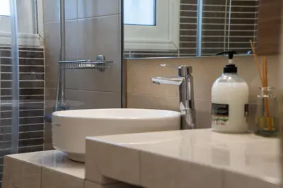 a bathroom with a sink and a bottle of soap at Palm & Pearl Apartment in Athens