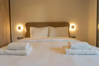 a large white bed with two towels on it at Palm & Pearl Apartment in Athens