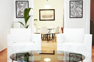 a dining room with white chairs and a glass table at Perikleous Apartment in Athens