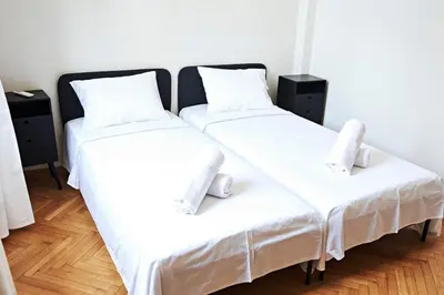 two beds in a room with white sheets and pillows at Perikleous Apartment in Athens