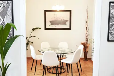a dining room with a glass table and white chairs at Perikleous Apartment in Athens