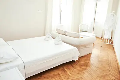 a white bedroom with a couch and a chair at Perikleous Apartment in Athens