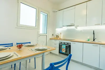 a kitchen with a wooden table and blue chairs at Ma de Bright Stay Attiki Metro in Athens