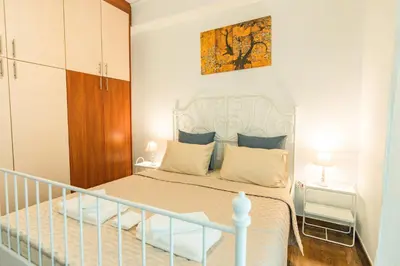 a bedroom with a white bed and a staircase at Ma de Bright Stay Attiki Metro in Athens