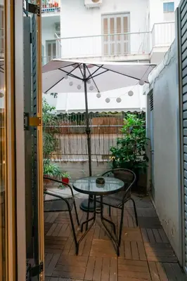 a patio with a table and chairs and an umbrella at The Athens Green Apt in Athens