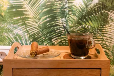 a cup of coffee sitting on a wooden table next to a plate with a cigar at The Athens Green Apt in Athens