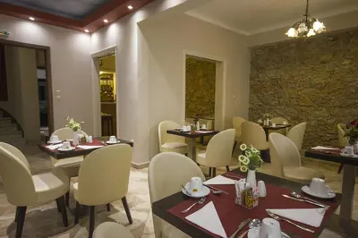 a restaurant with tables and chairs and a stone wall at Ambrosia Suites in Athens