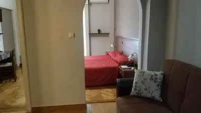a small bedroom with a red bed and a chair at Ambrosia Suites in Athens