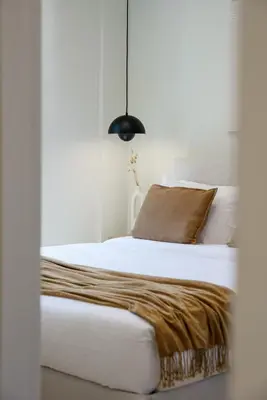 a bedroom with a white bed with a brown pillow at Acropolis Dream with Plunge Pool in Athens