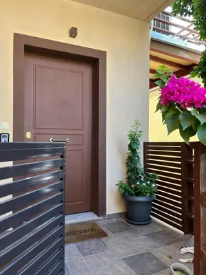 a red door on the side of a house with flowers at Michael Apartment, near the Airport in Koropíon
