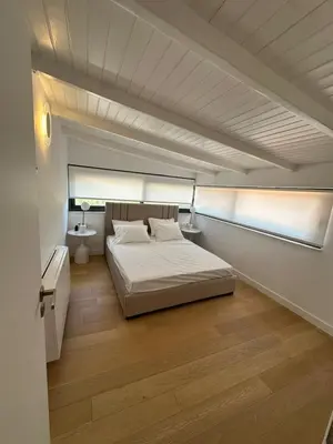 a bedroom with a white bed and a wooden floor at Penthouse with sea view in Athens