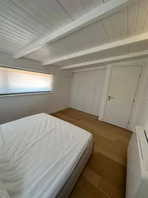 a bedroom with a white bed and a door at Penthouse with sea view in Athens