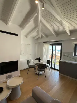 a living room with a table and chairs and a tv at Penthouse with sea view in Athens