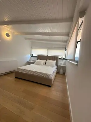 a bedroom with a white bed and a wooden floor at Penthouse with sea view in Athens