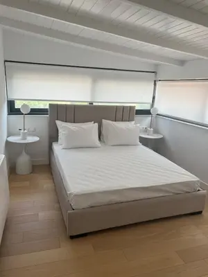 a bedroom with a bed with white sheets and two tables at Penthouse with sea view in Athens