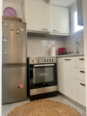 a kitchen with a stainless steel refrigerator and white cabinets at Roof Garden Home in Athens