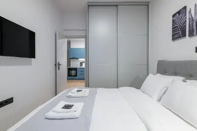 a bedroom with a white bed with a flat screen tv at The Athens Getaway Apartment GF in Athens