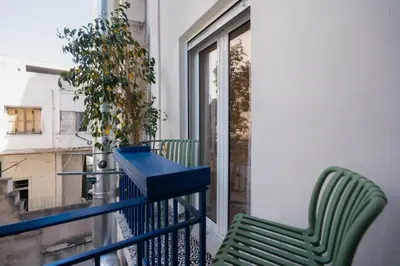 a balcony with a green chair and a window at 1BR Next to Metro Modern Comfort in Athens