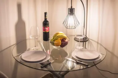a glass table with a bowl of fruit and a bottle of wine at Cozy home in the heart of Athens in Athens