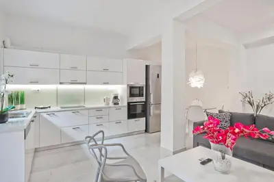 a kitchen and living room with white cabinets and a table at Serenity in the city - Stylish 1bd Garden Flat in Athens