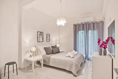 a white bedroom with a bed and a window at Serenity in the city - Stylish 1bd Garden Flat in Athens
