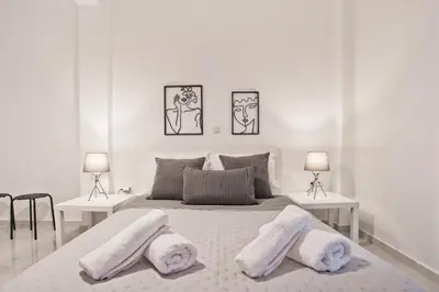 a white bedroom with a large bed with three pillows at Serenity in the city - Stylish 1bd Garden Flat in Athens