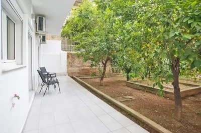a courtyard with two chairs and trees on a house at Serenity in the city - Stylish 1bd Garden Flat in Athens