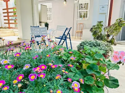 a garden with flowers and chairs on a patio at Zoy's house in Athens
