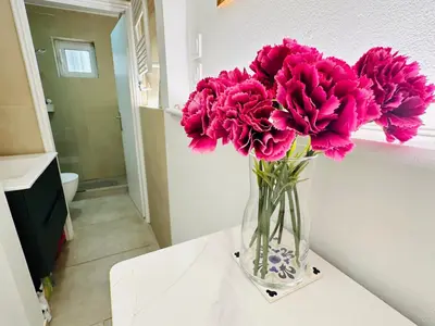 a vase filled with pink flowers sitting on a table at Zoy's house in Athens