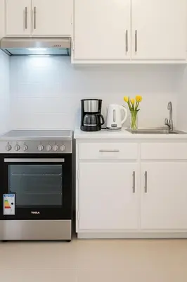 a kitchen with white cabinets and a black oven at Saronida BEACH STUDIO in Saronida