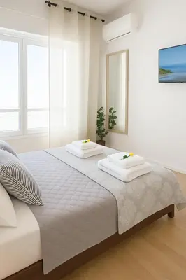 a white bedroom with a large bed with two white pillows at Saronida BEACH STUDIO in Saronida
