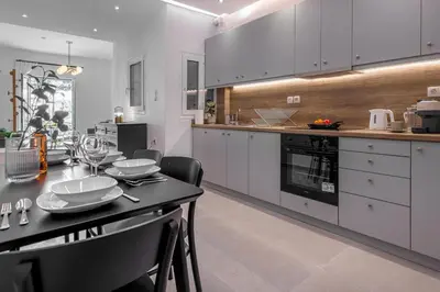 a kitchen with white cabinets and a table with chairs at Stylish & Bright Flat Across Metro - 8' to Center in Athens