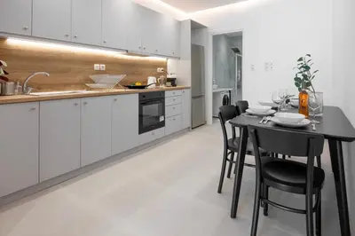 a kitchen with white cabinets and a black table and chairs at Stylish & Bright Flat Across Metro - 8' to Center in Athens