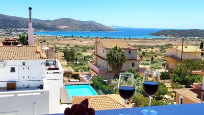 two glasses of wine on a balcony with a view of the ocean at Villa Golden Sun with swimming pool and jacuzzi in Anavissos