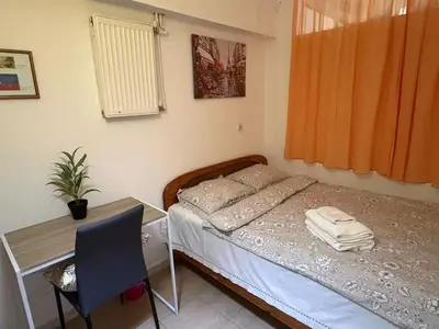 a bedroom with a bed and a desk and a table at Cozy lower ground floor apartment by Sea and Tram in Athens